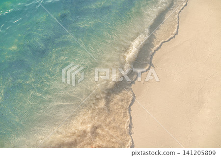 Crystal clear shallow water meeting white sand from above, diagonal shoreline composition. Transparent sea revealing textured seabed, fresh green tinted tropical water edge. Clean aerial style Crystal clear shallow water meeting white sand from above, diagonal shoreline composition. Transparent sea revealing textured seabed, fresh green tinted tropical water edge. Clean aerial style 141205809