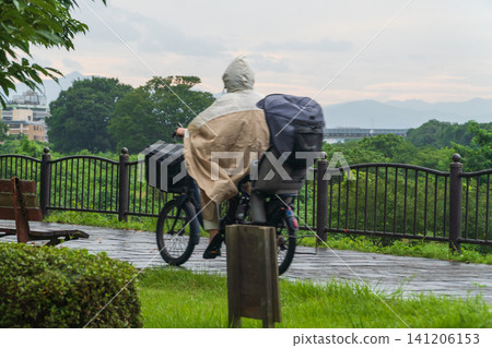 下雨天，一位女士穿著雨衣騎著腳踏車。 141206153