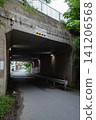 A tunnel beneath the road with a roadway and sidewalk that is lit even during the daytime. 141206568
