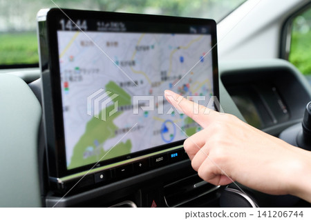 一位亞洲女性正在操作汽車導航系統。 141206744