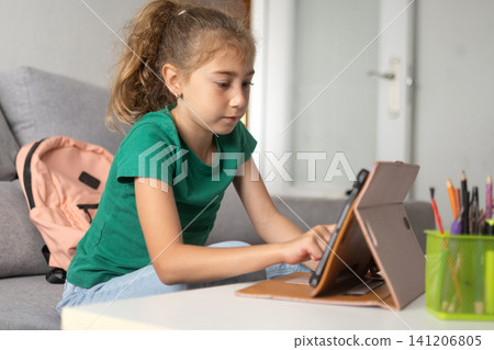 Focused schoolgirl using a tablet for online learning at home Focused schoolgirl using a tablet for online learning at home 141206805