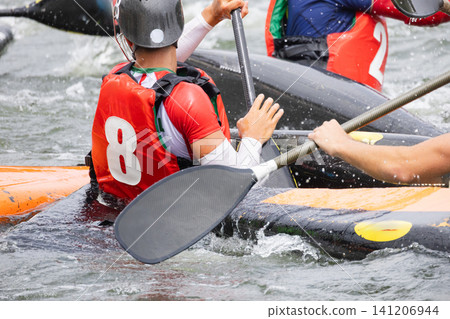 Canoe polo players in colorful jerseys maneuvering their kayaks on a river, with splashes of water and paddles visible in an active sports setting Canoe polo players in colorful jerseys maneuvering their kayaks on a river, with splashes of water and paddles visible in an active sports setting 141206944