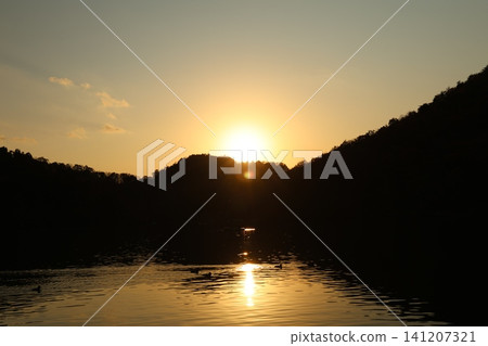 A calm lake surface and a sunset A calm lake surface and a sunset 141207321