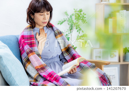 一位女士正在看書；她似乎感冒了。 141207670