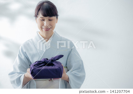 A woman in a kimono holding a wrapping cloth A woman in a kimono holding a wrapping cloth 141207704