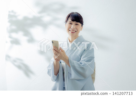 一位身穿和服的女子正在使用智慧型手機 141207713