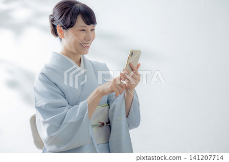 一位身穿和服的女子正在使用智慧型手機 141207714