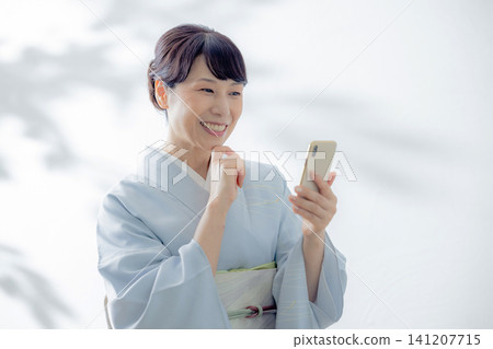 一位身穿和服的女子正在使用智慧型手機 一位身穿和服的女子正在使用智慧型手機 141207715