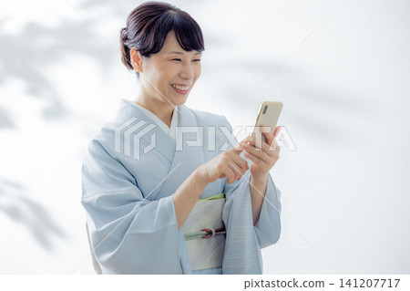 一位身穿和服的女子正在使用智慧型手機 一位身穿和服的女子正在使用智慧型手機 141207717