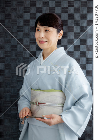 A woman getting dressed in a kimono 141207736