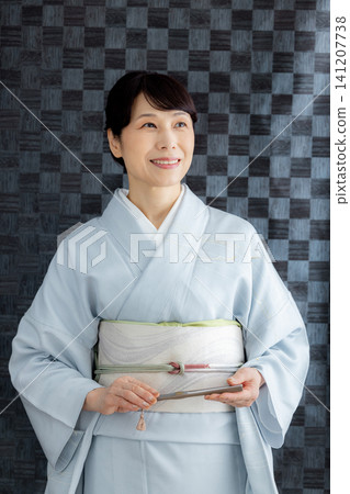 A woman getting dressed in a kimono A woman getting dressed in a kimono 141207738