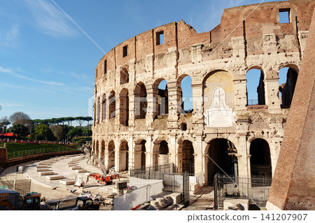 Group of workers repairs the exterior of the Colosseum in Rome in the morning light Group of workers repairs the exterior of the Colosseum in Rome in the morning light 141207907