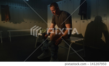 Determined Young Man with Leg Prosthetic Changing Clothes in Sports Facility Determined Young Man with Leg Prosthetic Changing Clothes in Sports Facility 141207950