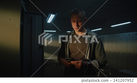 Young Man Checking Fitness App on Smartphone in Gym Locker Room Before Workout Young Man Checking Fitness App on Smartphone in Gym Locker Room Before Workout 141207952