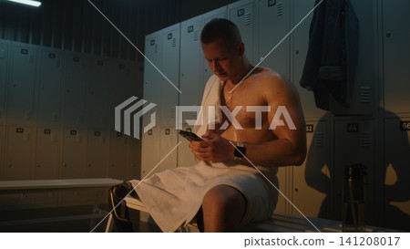 Amputee Athlete Using Smartphone while Resting in Locker Room After Shower Amputee Athlete Using Smartphone while Resting in Locker Room After Shower 141208017