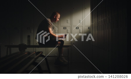 Resilient Man with Leg Prosthesis Texting His Coach in Locker Room Resilient Man with Leg Prosthesis Texting His Coach in Locker Room 141208026
