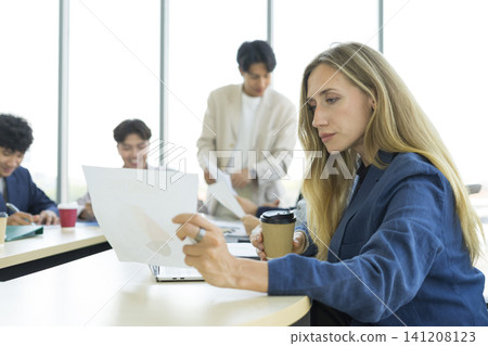 Teamwork. Side view of white woman in a office using laptop during creative meeting and drink coffee. Concept of business, office, finance, open space. Teamwork. Side view of white woman in a office using laptop during creative meeting and drink coffee. Concept of business, office, finance, open space. 141208123