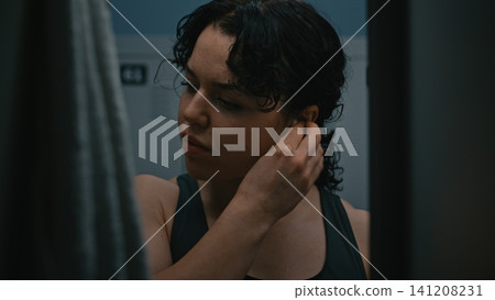 Focused Young Female Athlete Puts on Wireless Headphones and Checks Smartphone in Locker Room Focused Young Female Athlete Puts on Wireless Headphones and Checks Smartphone in Locker Room 141208231