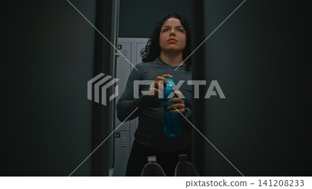 Sporty Female Changing Clothes and Drinking Water in Gym Sporty Female Changing Clothes and Drinking Water in Gym 141208233