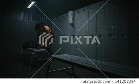 Young Female Athlete Tying Sneakers Before Workout in Gym Locker Room Young Female Athlete Tying Sneakers Before Workout in Gym Locker Room 141208384