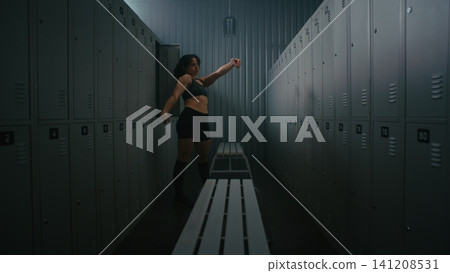 Athletic Woman Taking Selfie and Flexing Biceps in Gym Locker Room Athletic Woman Taking Selfie and Flexing Biceps in Gym Locker Room 141208531