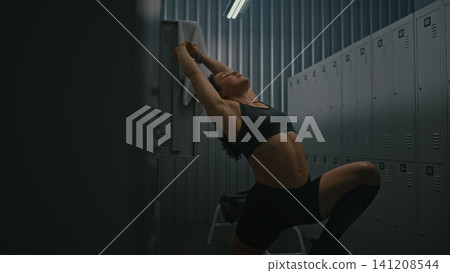 Pre workout Stretching Routine, Athletic Woman in Moody Locker Room Pre workout Stretching Routine, Athletic Woman in Moody Locker Room 141208544