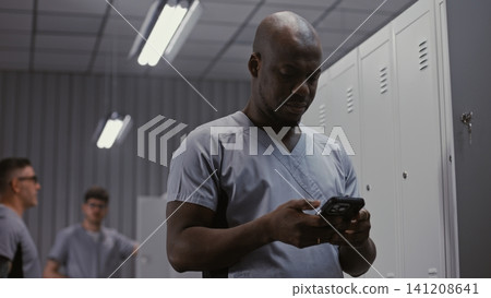 Tired Doctor Checking Messages and Changing Clothes at Locker after Long Hospital Shift Tired Doctor Checking Messages and Changing Clothes at Locker after Long Hospital Shift 141208641