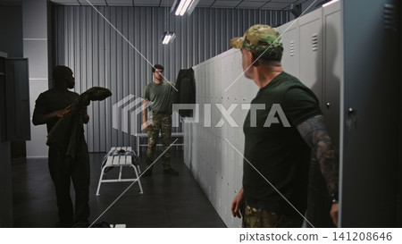 Diverse Military Officers Prepare For Training in Base Locker Room, Sharing Light Conversation Diverse Military Officers Prepare For Training in Base Locker Room, Sharing Light Conversation 141208646