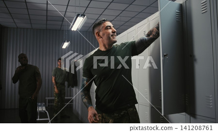 Soldiers Relaxing, Talking, and Undressing in Military Base Locker Room after Finished Mission 141208761