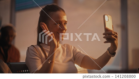 Young Female Passenger Using Smartphone for Video Conversation in Airport Lounge Young Female Passenger Using Smartphone for Video Conversation in Airport Lounge 141208800
