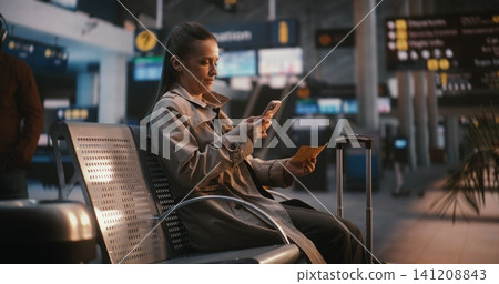 Elegant Woman in Trench Coat Arriving at Airport Waiting Area with Suitcase Elegant Woman in Trench Coat Arriving at Airport Waiting Area with Suitcase 141208843