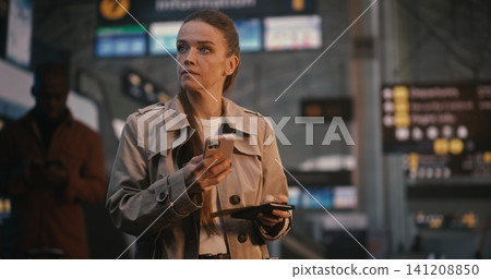 Elegant Woman in Trench Coat Scanning Mobile Ticket and Checking Flight Board Elegant Woman in Trench Coat Scanning Mobile Ticket and Checking Flight Board 141208850
