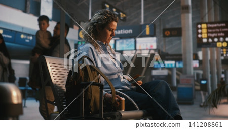 Woman Checking Flight Details and Drinking Coffee in Airport Lounge Woman Checking Flight Details and Drinking Coffee in Airport Lounge 141208861