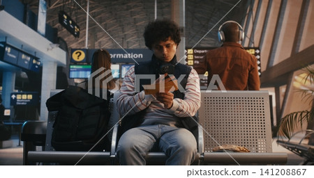 Young Male Passenger Scanning Digital Ticket and Walking to Boarding Gate 141208867