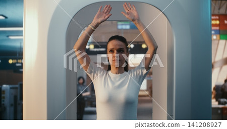 Focused Woman in White T Shirt Following Security Procedures During Airport Body Inspection Focused Woman in White T Shirt Following Security Procedures During Airport Body Inspection 141208927