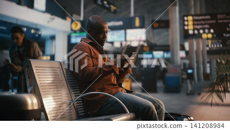 Adult Man with Suitcase Arriving at Gate and Checking Digital Ticket Adult Man with Suitcase Arriving at Gate and Checking Digital Ticket 141208984