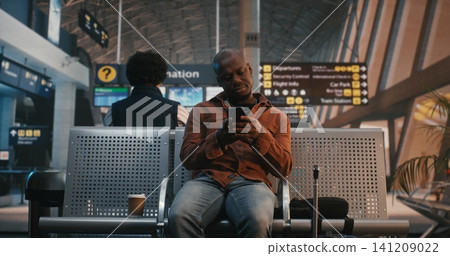 African American Traveler Checking Smartphone Notifications in Airport Lounge African American Traveler Checking Smartphone Notifications in Airport Lounge 141209022