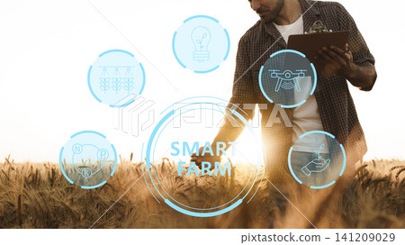 Smart farm technology in use by farmer working in field at sunset Smart farm technology in use by farmer working in field at sunset 141209029