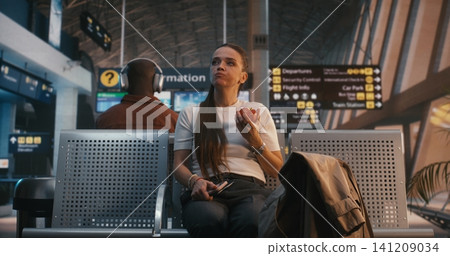 Young Caucasian Woman Eating Red Apple and Using Smartphone at Airport Young Caucasian Woman Eating Red Apple and Using Smartphone at Airport 141209034
