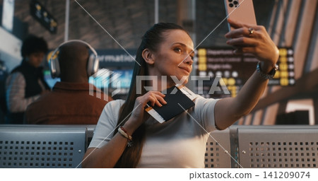 Young Female Traveler Taking Selfie with Boarding Pass at Airport Gate Young Female Traveler Taking Selfie with Boarding Pass at Airport Gate 141209074
