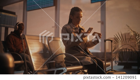 Elegant Woman in Trench Coat Sitting in Airport Lounge with Runway View and Scanning Ticket Elegant Woman in Trench Coat Sitting in Airport Lounge with Runway View and Scanning Ticket 141209091