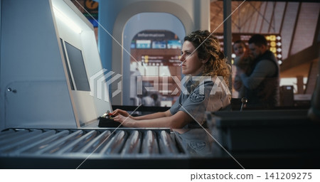 Female Airport Security Officer Monitoring Xray Scanner at Passenger Checkpoint Female Airport Security Officer Monitoring Xray Scanner at Passenger Checkpoint 141209275