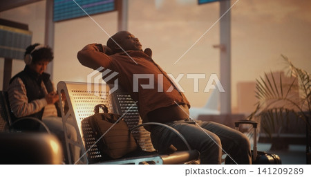 Relaxed Traveler Stretching and Looking at Airplanes Through Airport Window 141209289