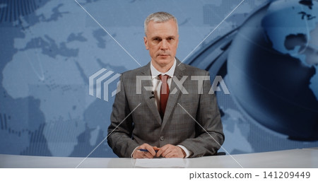 Mature Male Financial News Anchor Reporting on Global Markets in Modern Television Studio Mature Male Financial News Anchor Reporting on Global Markets in Modern Television Studio 141209449
