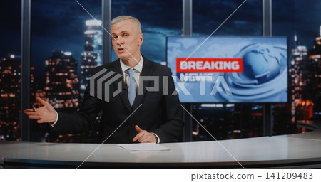 Mature Male News Anchor Explaining Breaking News Events sitting at Desk in Digital TV Studio Mature Male News Anchor Explaining Breaking News Events sitting at Desk in Digital TV Studio 141209483