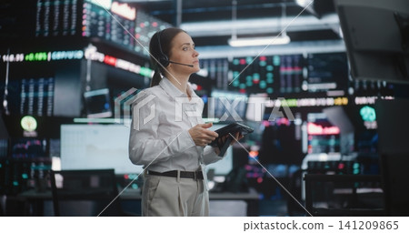 Focused Female Broker Manages Market Activity on Busy Trading Floor 141209865