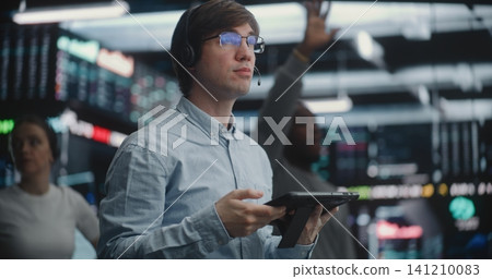 Male Financial Analyst in Blue Shirt Using Hand Gestures Execute Trades at Stock Market Male Financial Analyst in Blue Shirt Using Hand Gestures Execute Trades at Stock Market 141210083