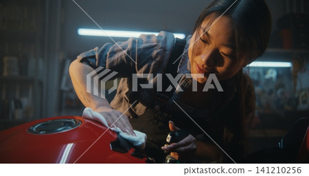 Biker Girl Admiring Sunlight In Sun Drenched Industrial Garage. Biker Girl Admiring Sunlight In Sun Drenched Industrial Garage. 141210256