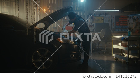 Skilled Female Technician in Work Overalls Shown Refilling Engine With Fresh Motor Oil Skilled Female Technician in Work Overalls Shown Refilling Engine With Fresh Motor Oil 141210272