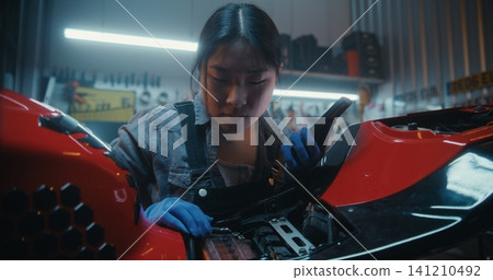 Young Woman Repairing Motorcycle in Modern Garage Uses Smartphone With Voice AI Assistant Young Woman Repairing Motorcycle in Modern Garage Uses Smartphone With Voice AI Assistant 141210492